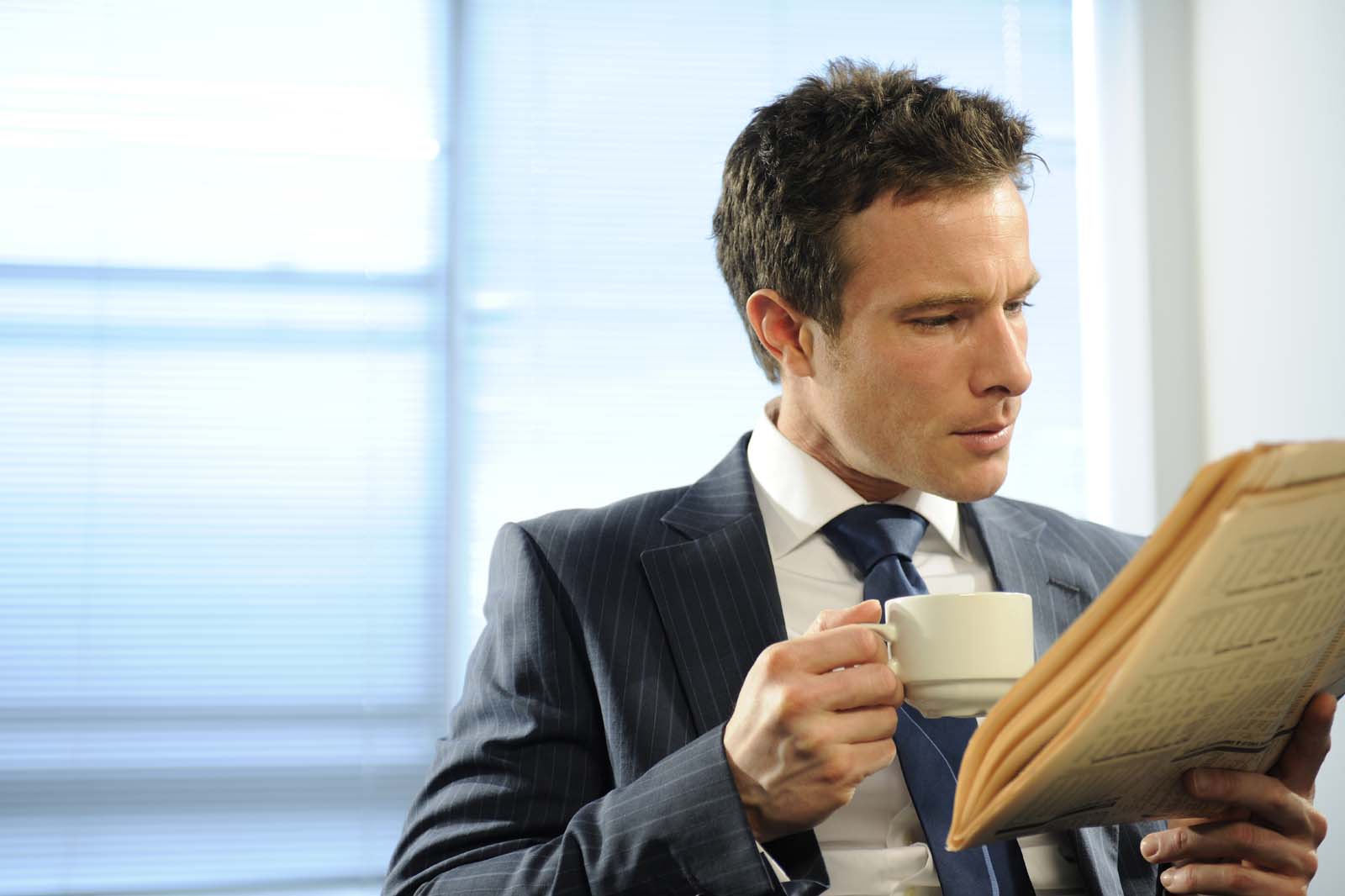 person drinking coffee in an office setting while looking at documents