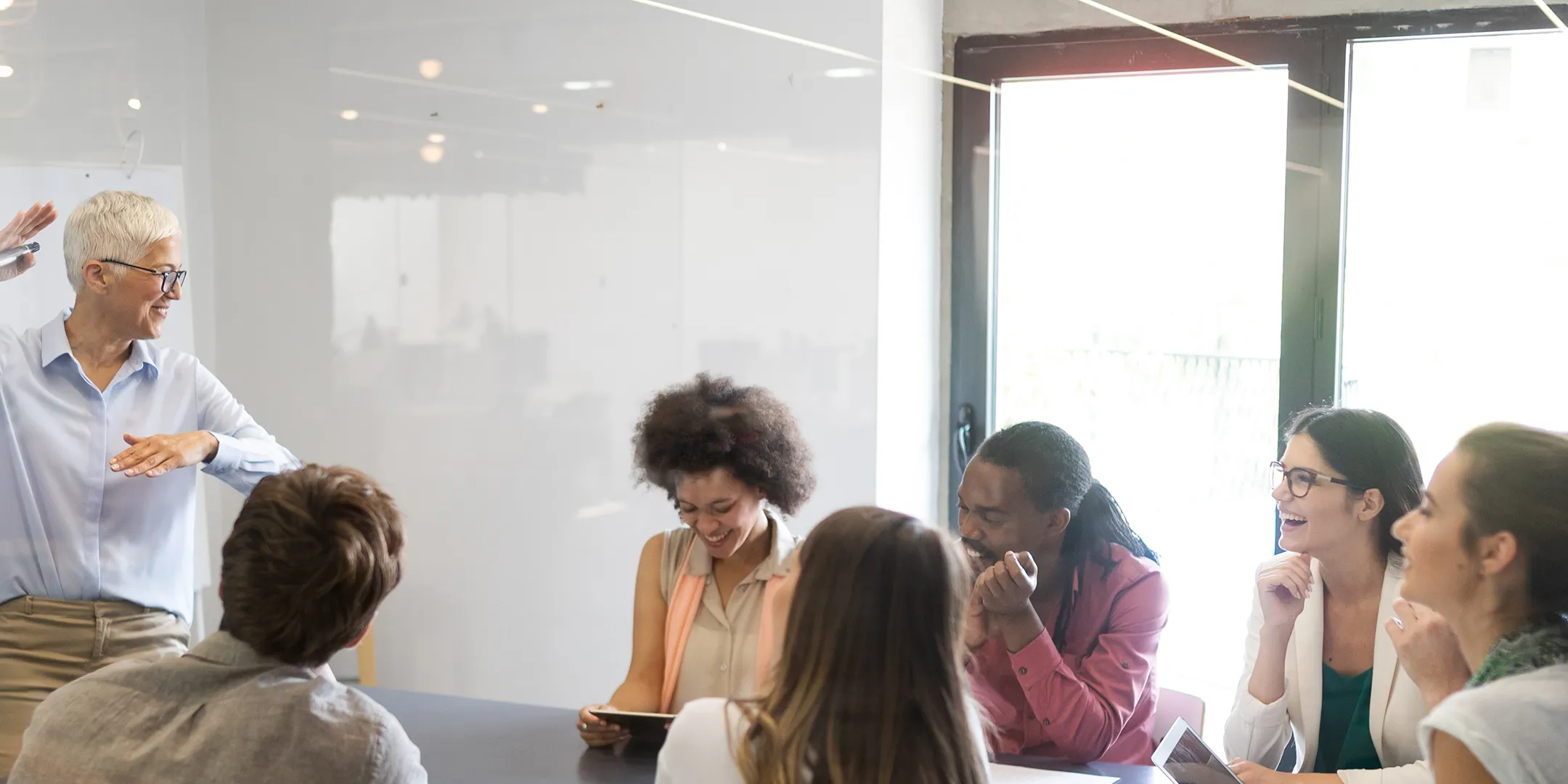 A diverse group of professionals discussing business insights for success in a meeting room labeled "MMP Your Business Insights for Success."