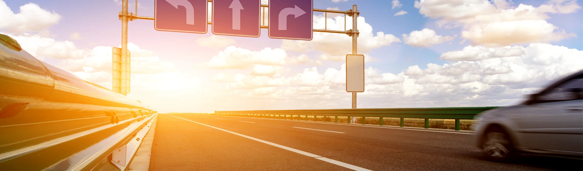 Highway at sunset showing different directional signs.