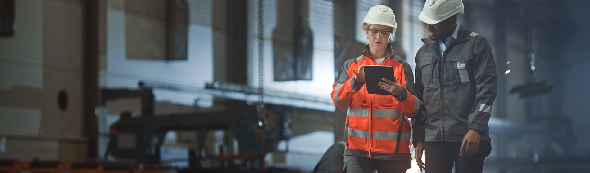 Male and female workers in PPE looking at a tablet