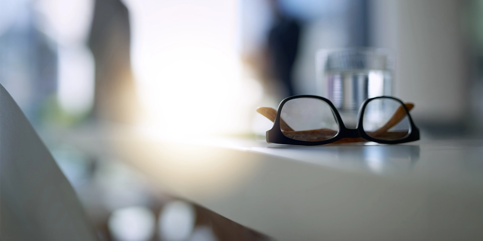 lunettes sur un bureau avec des gens qui parlent en arrière-plan flou