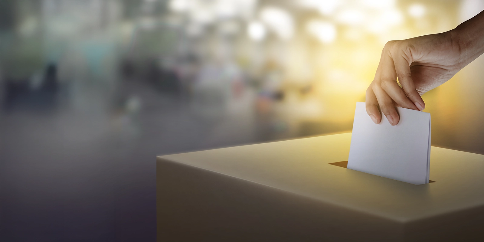 women hand putting paper with vote into ballot box