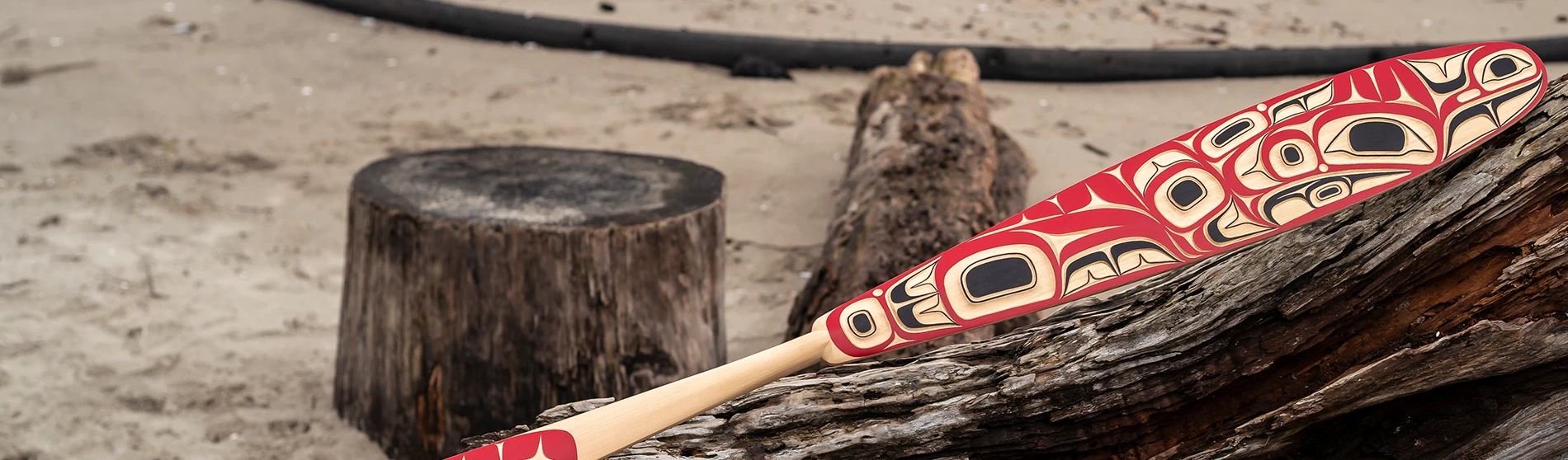 Painted cedar paddle on a beach