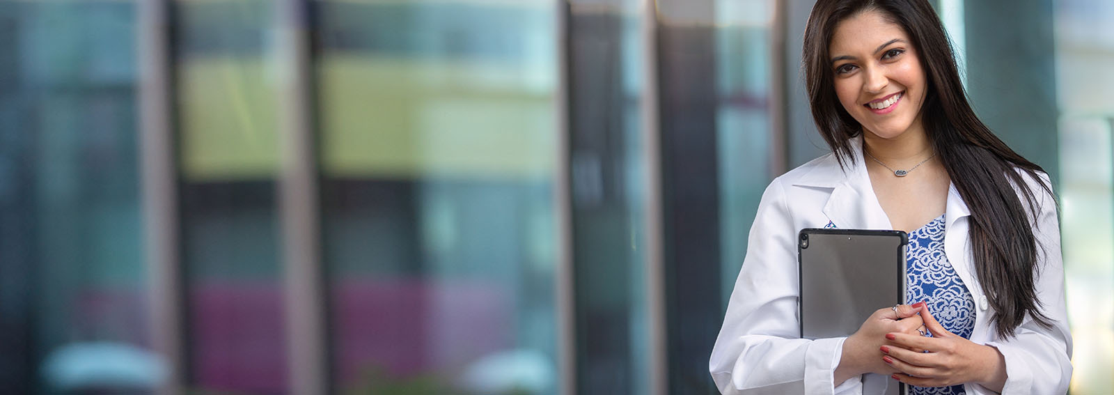 Smiling dental student holding a laptop.