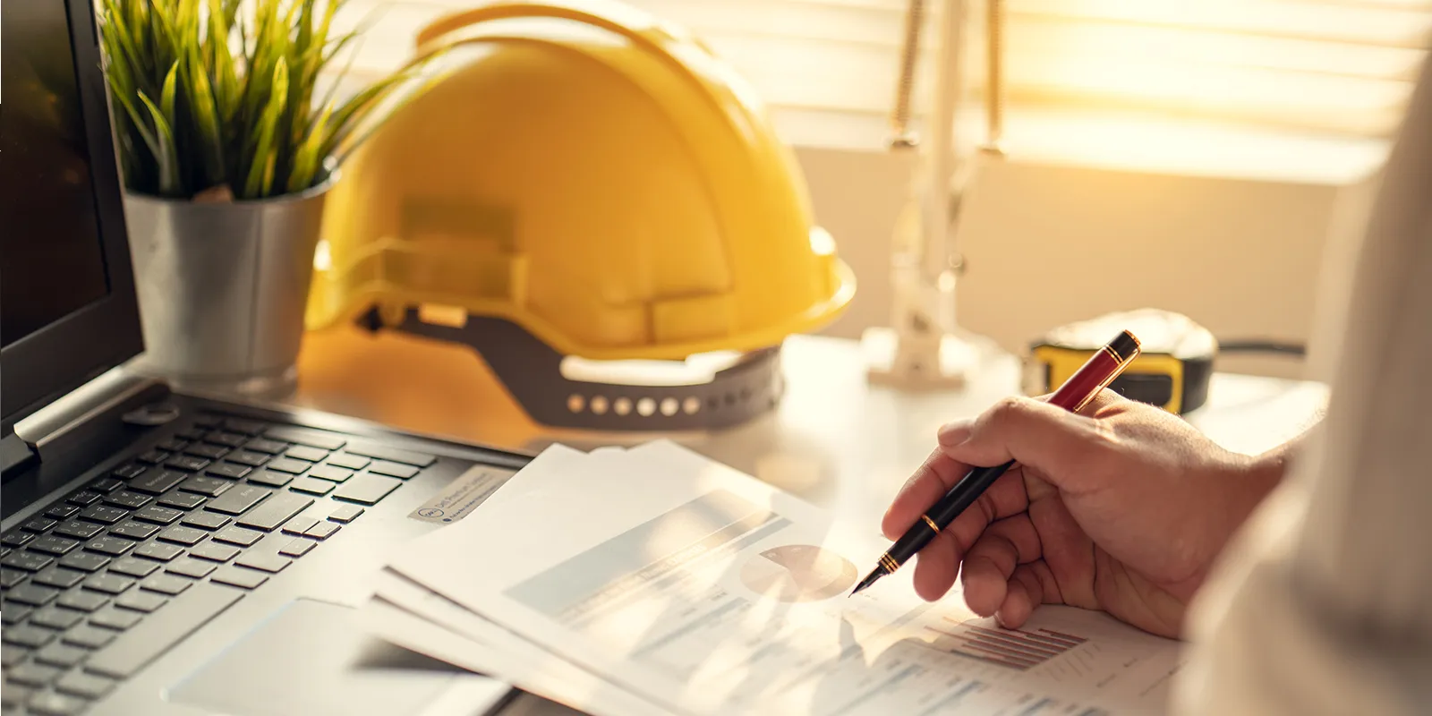 Chef de chantier écrivant dans un bureau avec un ordinateur portable à un bureau.