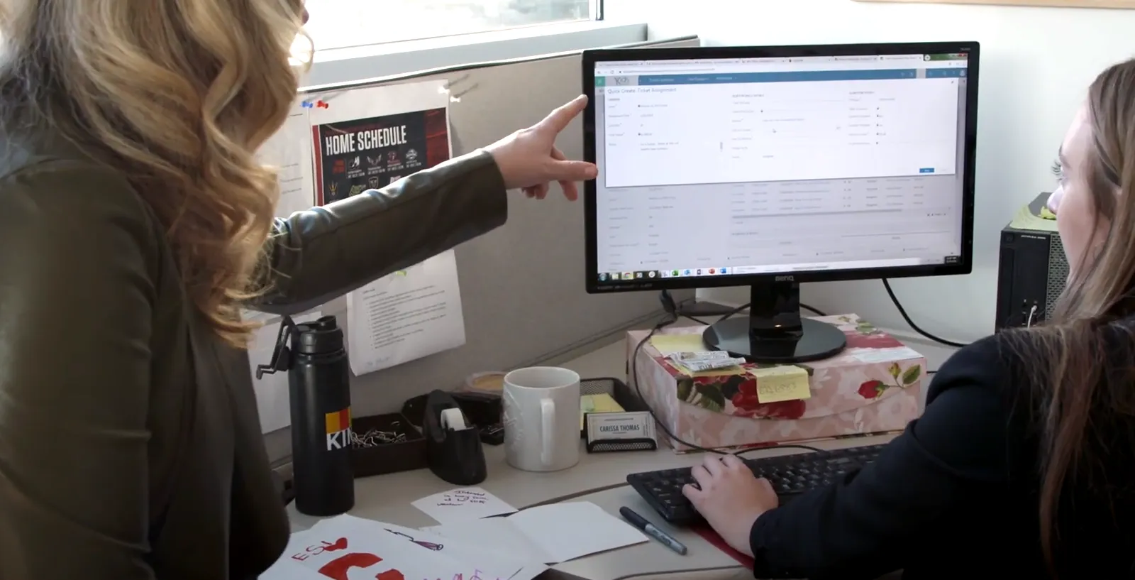 Woman pointing at computer screen on desk