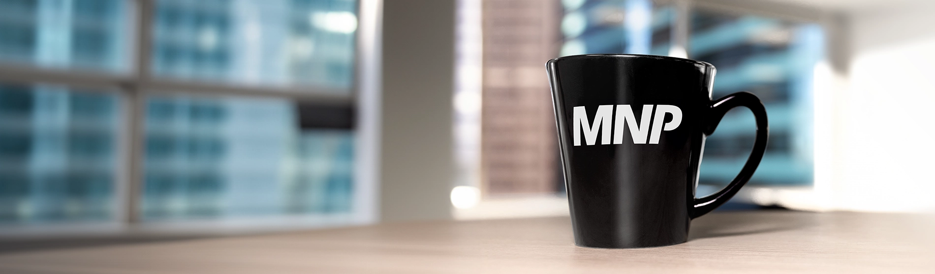 Black coffee mug with the MNP logo on a table 