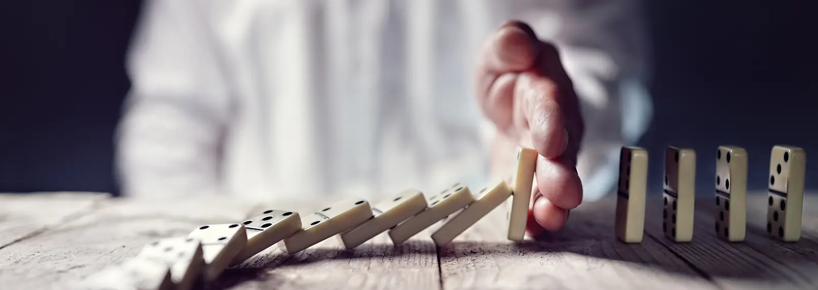 Dominos tombant sur une table en bois avec une personne en arrière-plan