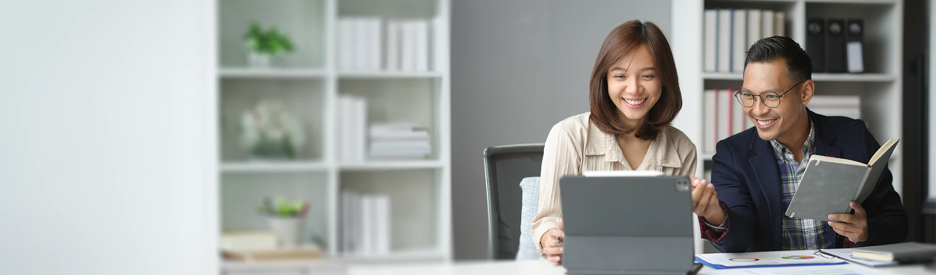 Two people analyzing data on a digital tablet and discussing accounting