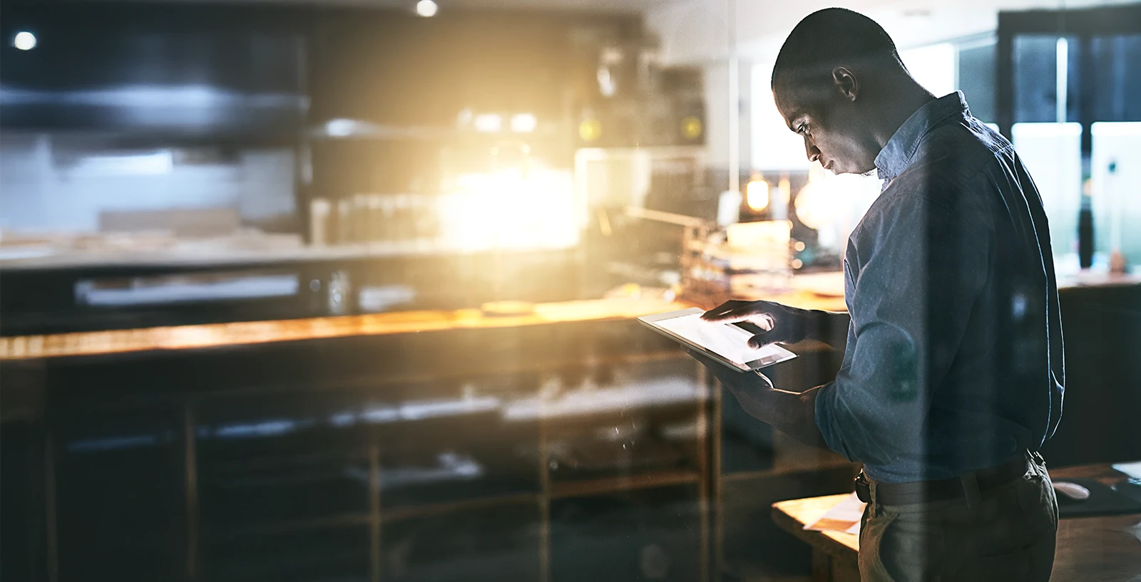 Man standing in office looking at tablet