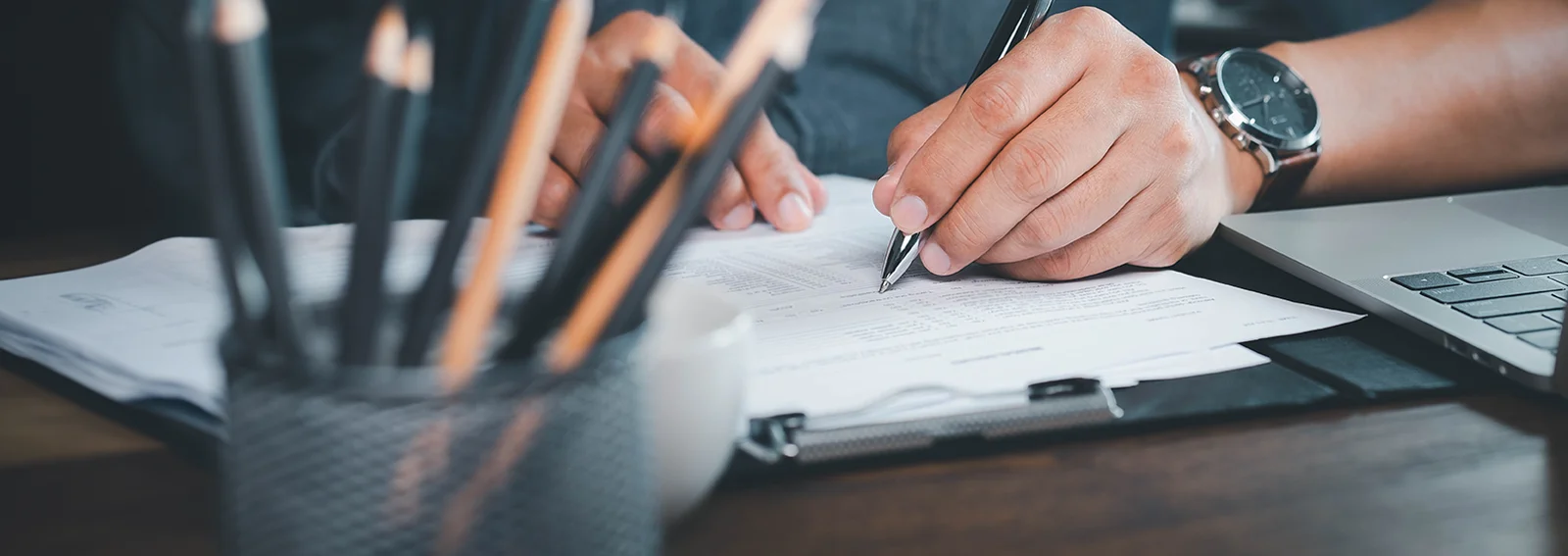 Close up of hand using writing pen with paperwork filling in business company personal information