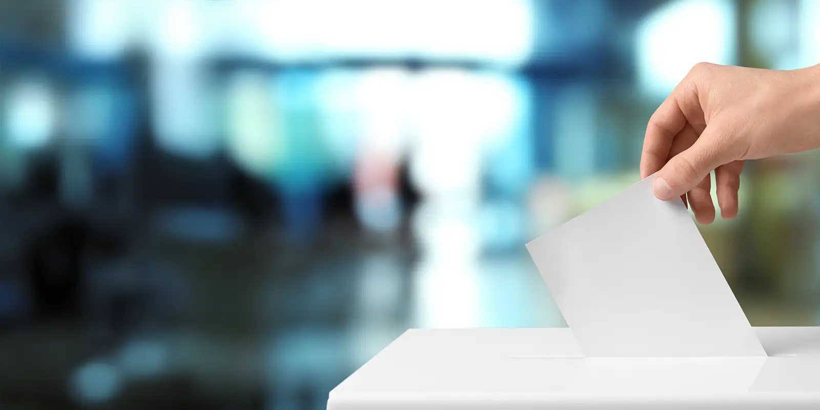 Close up person casting a vote into a box.