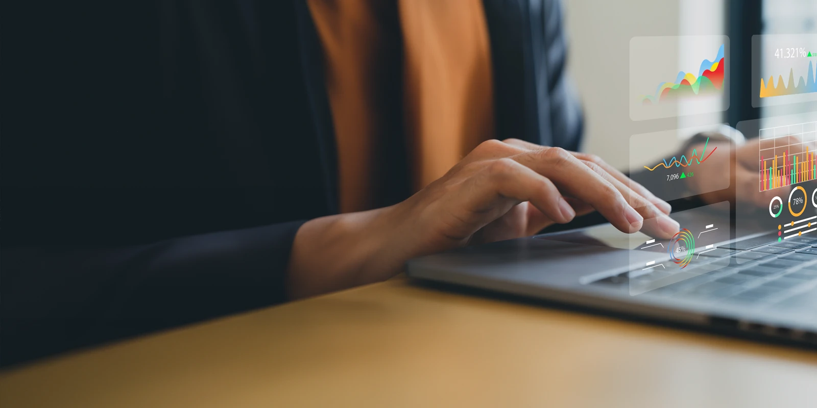 Close up of someone typing on a laptop with a graph hovering over their fingers.