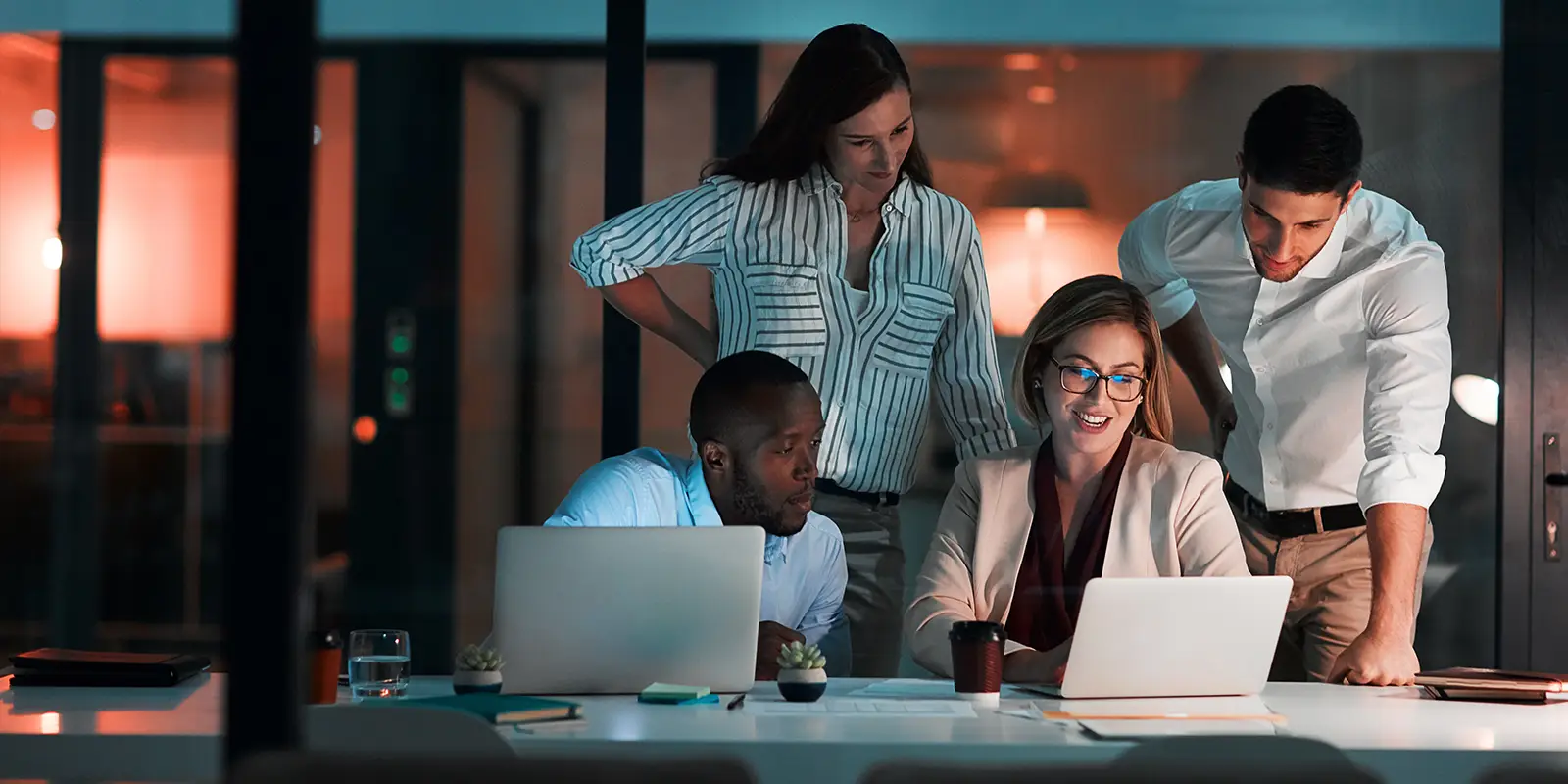 A diverse group of professionals collaborating on laptops in a modern office environment.