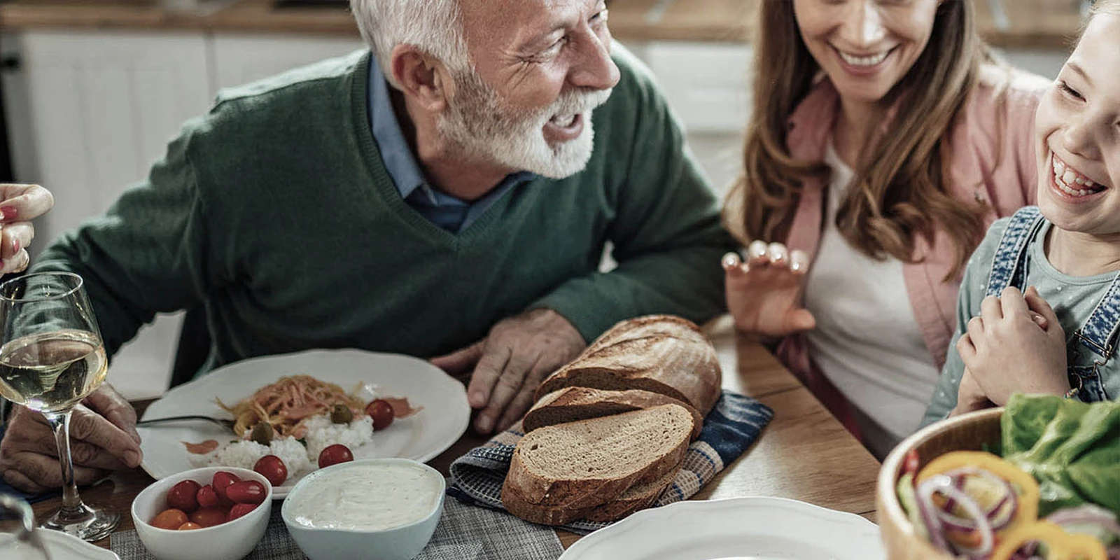 three generations of family members laughing at dinner table