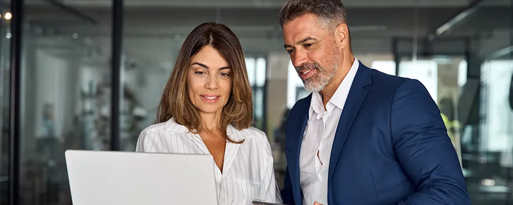 Two people having a conversation while referencing a laptop