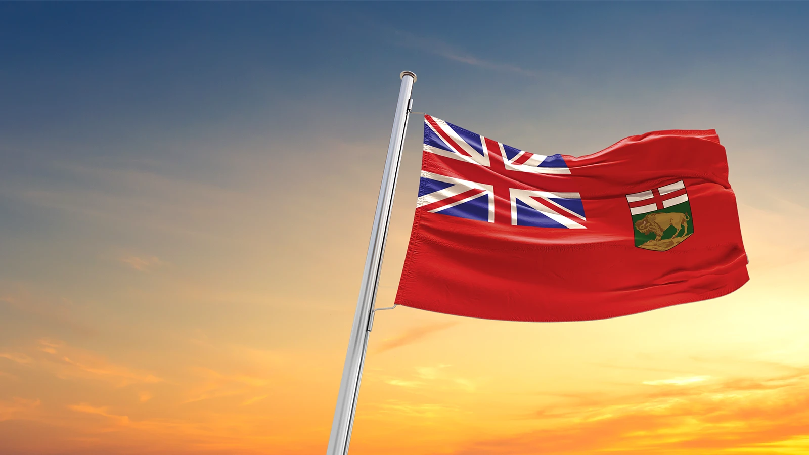 Manitoba flag blowing in wind with sunset background