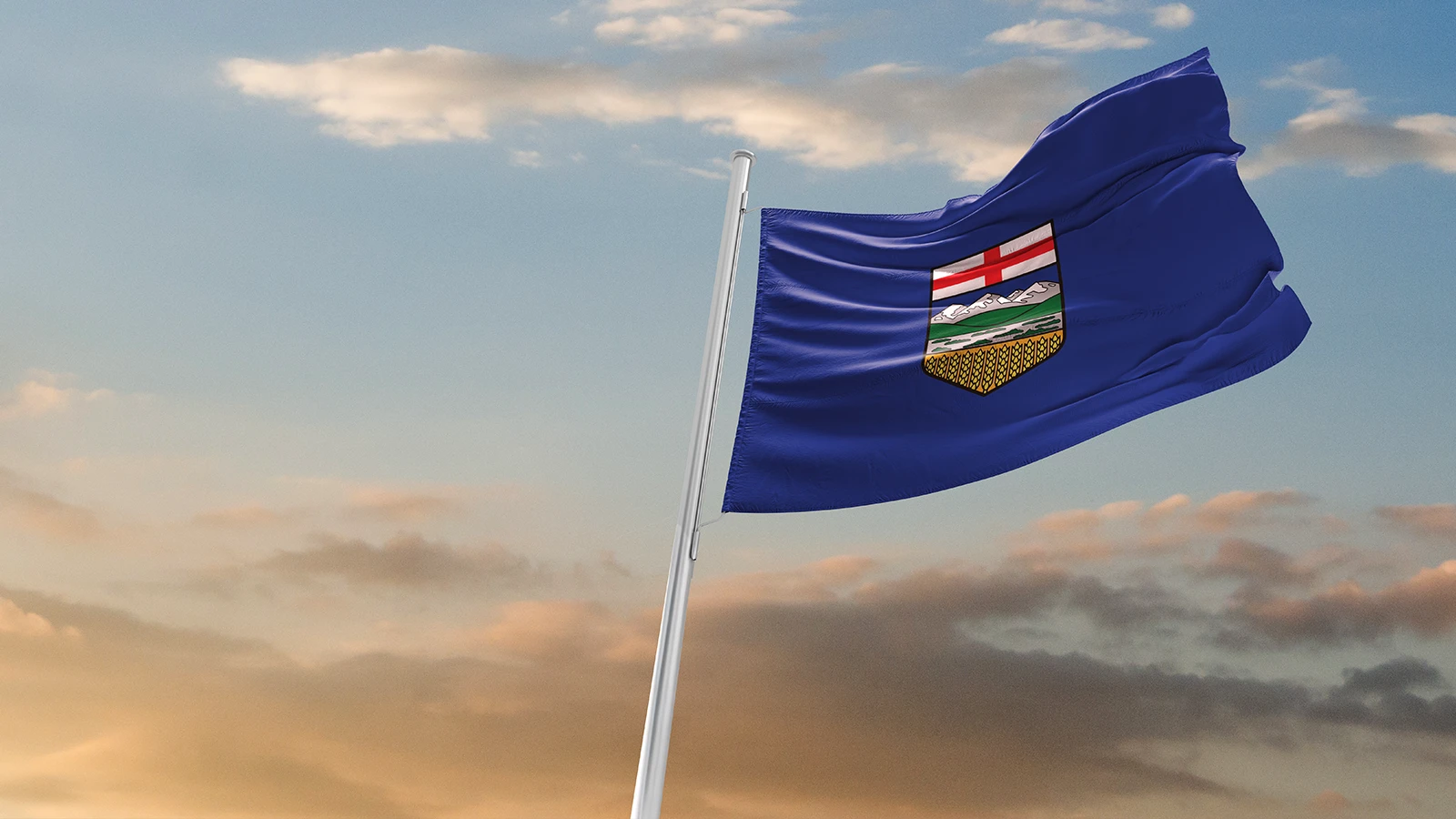 The flag of Alberta, Canada, waving against a backdrop of a cloudy sky during sunset.