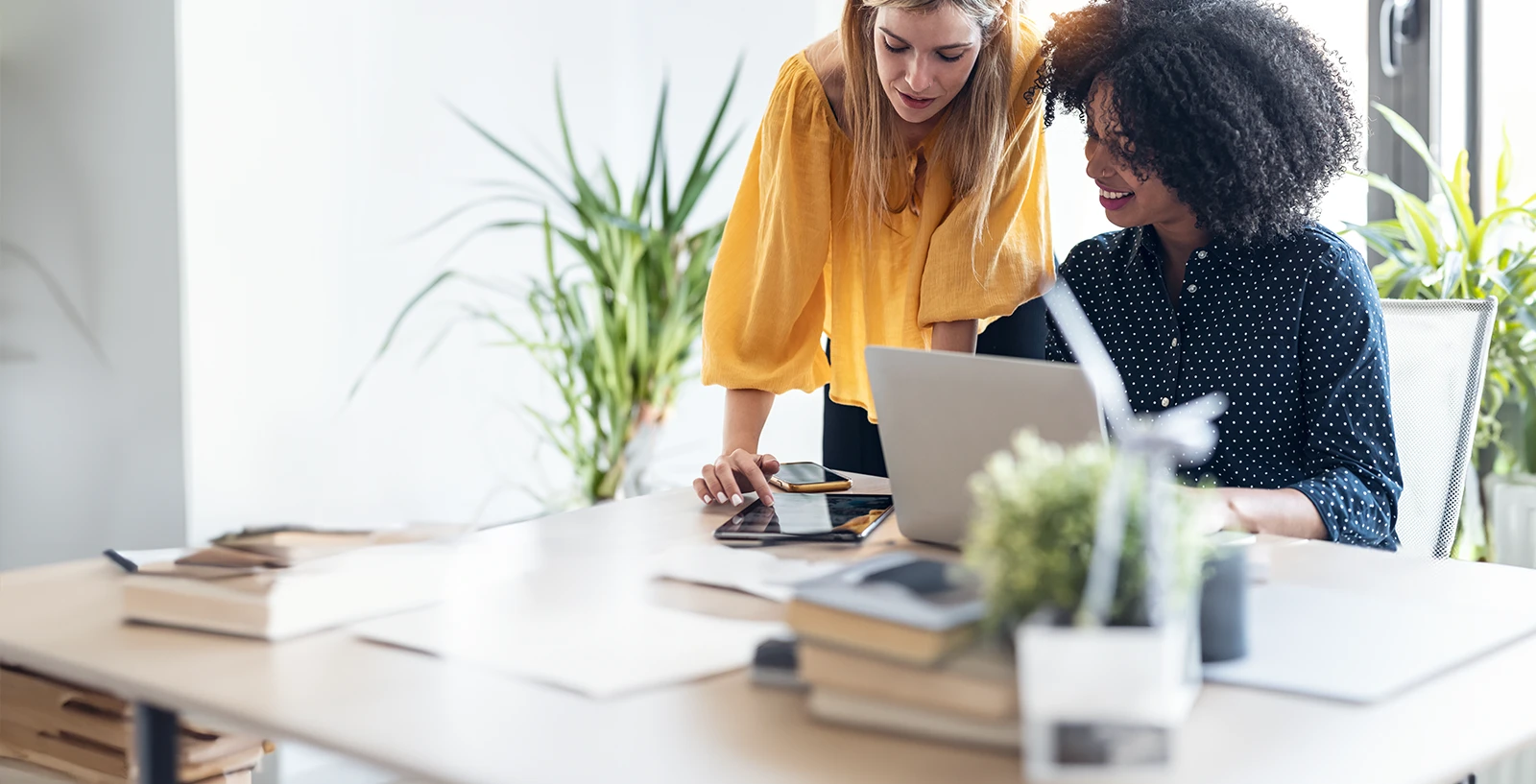 Two business woman working on a laptop.