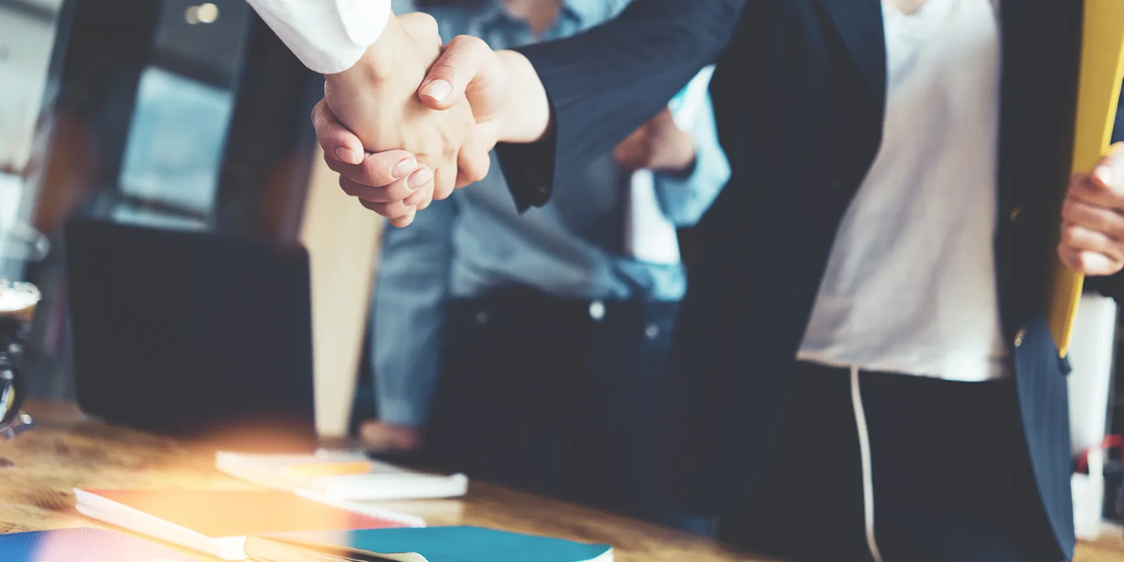 Business leader negotiating a transaction, shaking hands with another business leader at an office.